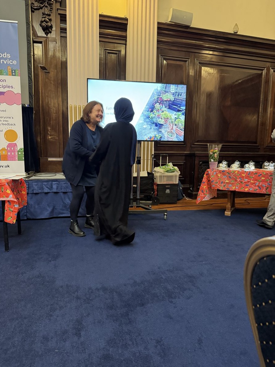 A speaker presenting beside a screen in an ornate hall